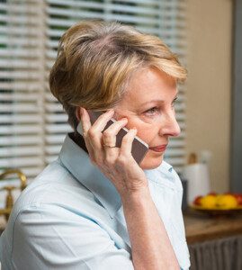 Senior woman on the phone at home in the kitchen