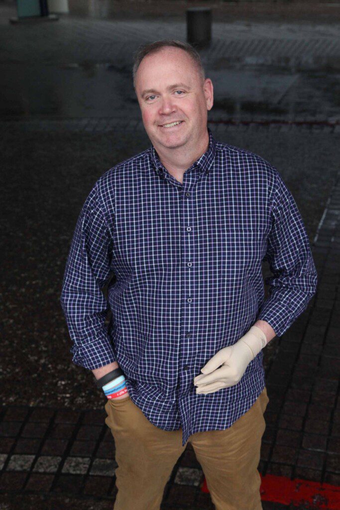 Man standing with a blue shirt and tan pants