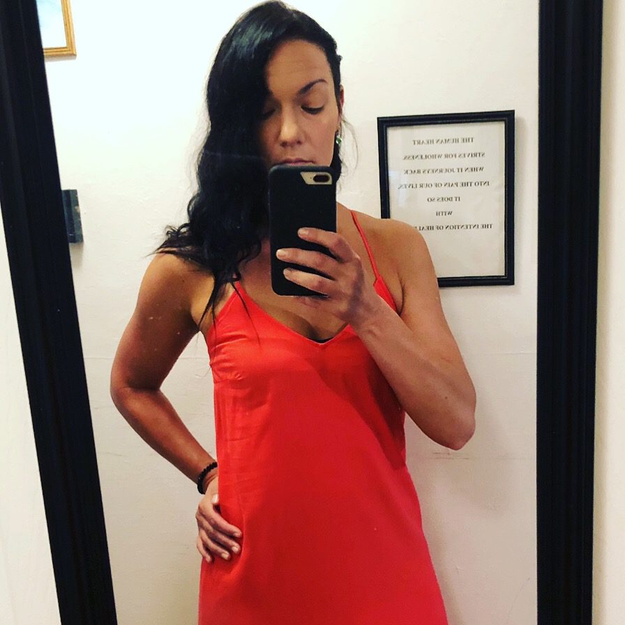 Dark haired woman taking a mirror photo in a red dress