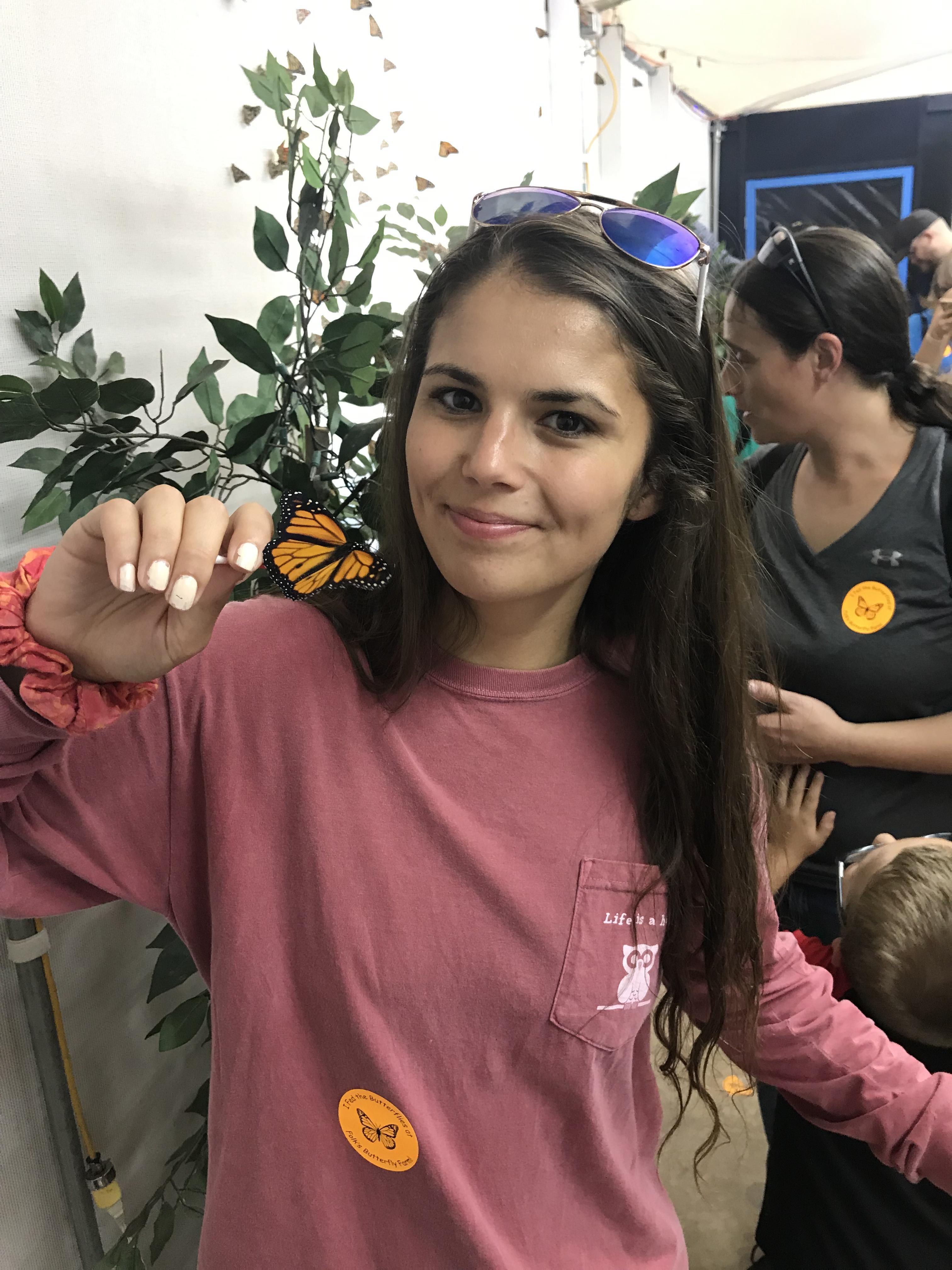 Woman in a red shirt holding a butterfly